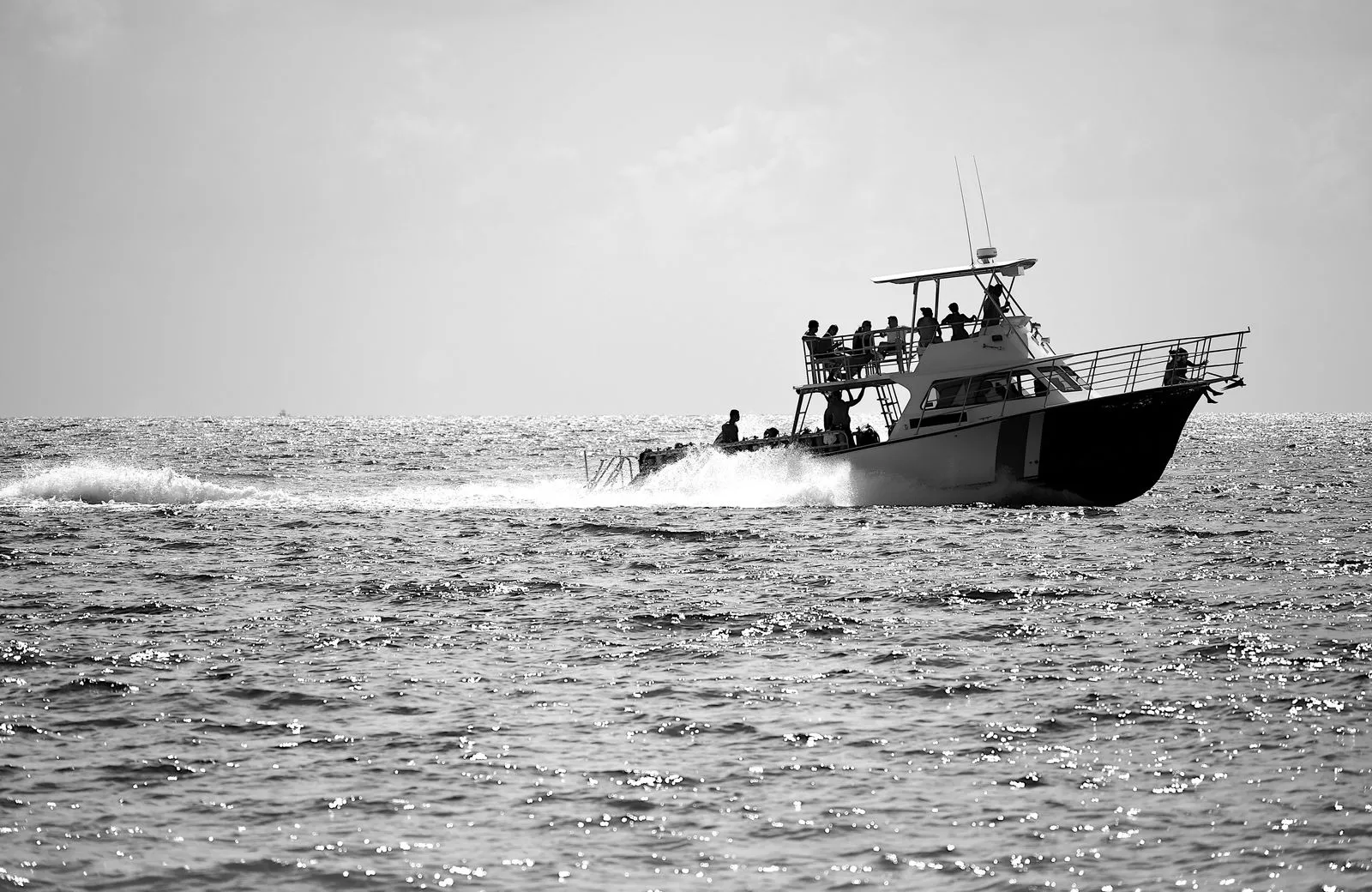 A motorboat navigating the ocean waves in a dynamic black and white shot.
